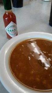 bowl of bean soup with a bottle of tabasco
