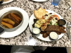 skillet of Greek potatoes and a platter of Greek food