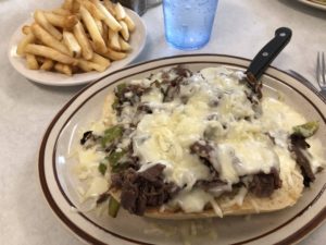 Open-faced Philly Cheese Steak with fries on a separate plate